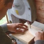 Das Elektrowerkzeug Kreissäge schneidet ein Stück Holz